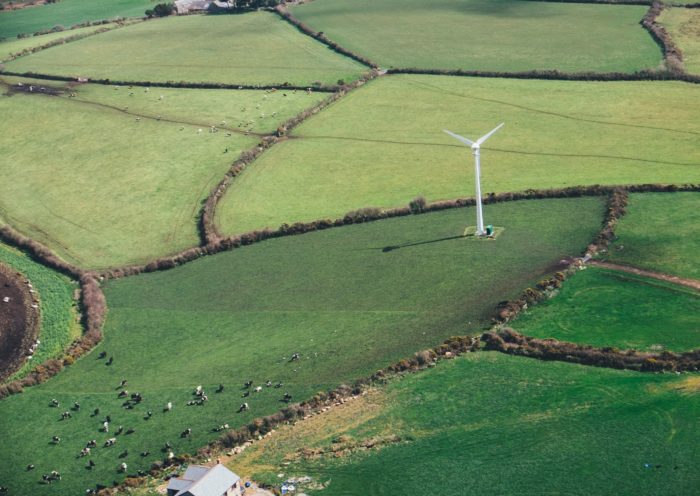 birds eye view of a wind mill in a grass field for green energy.