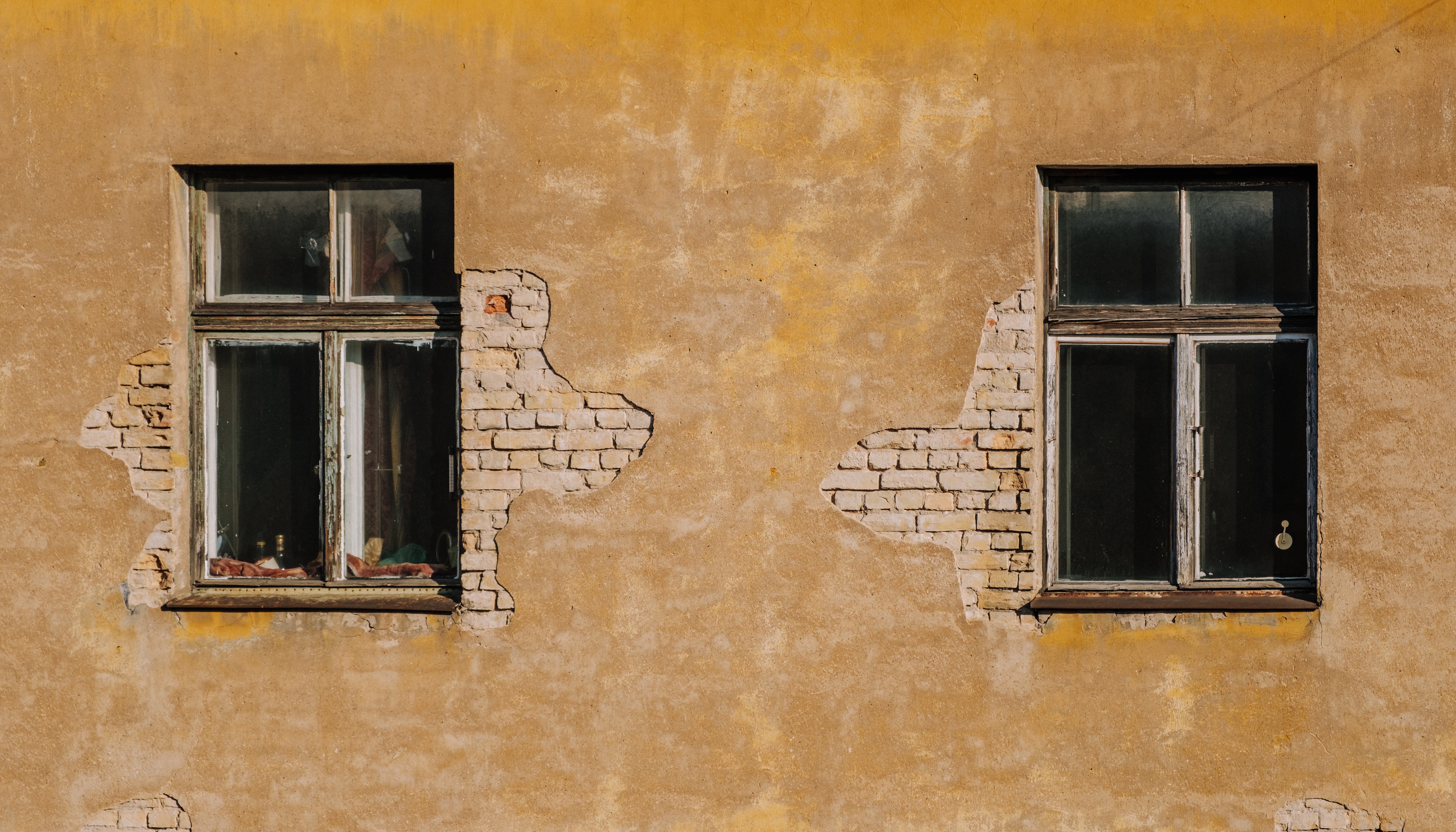 two windows on a roughed up wall
